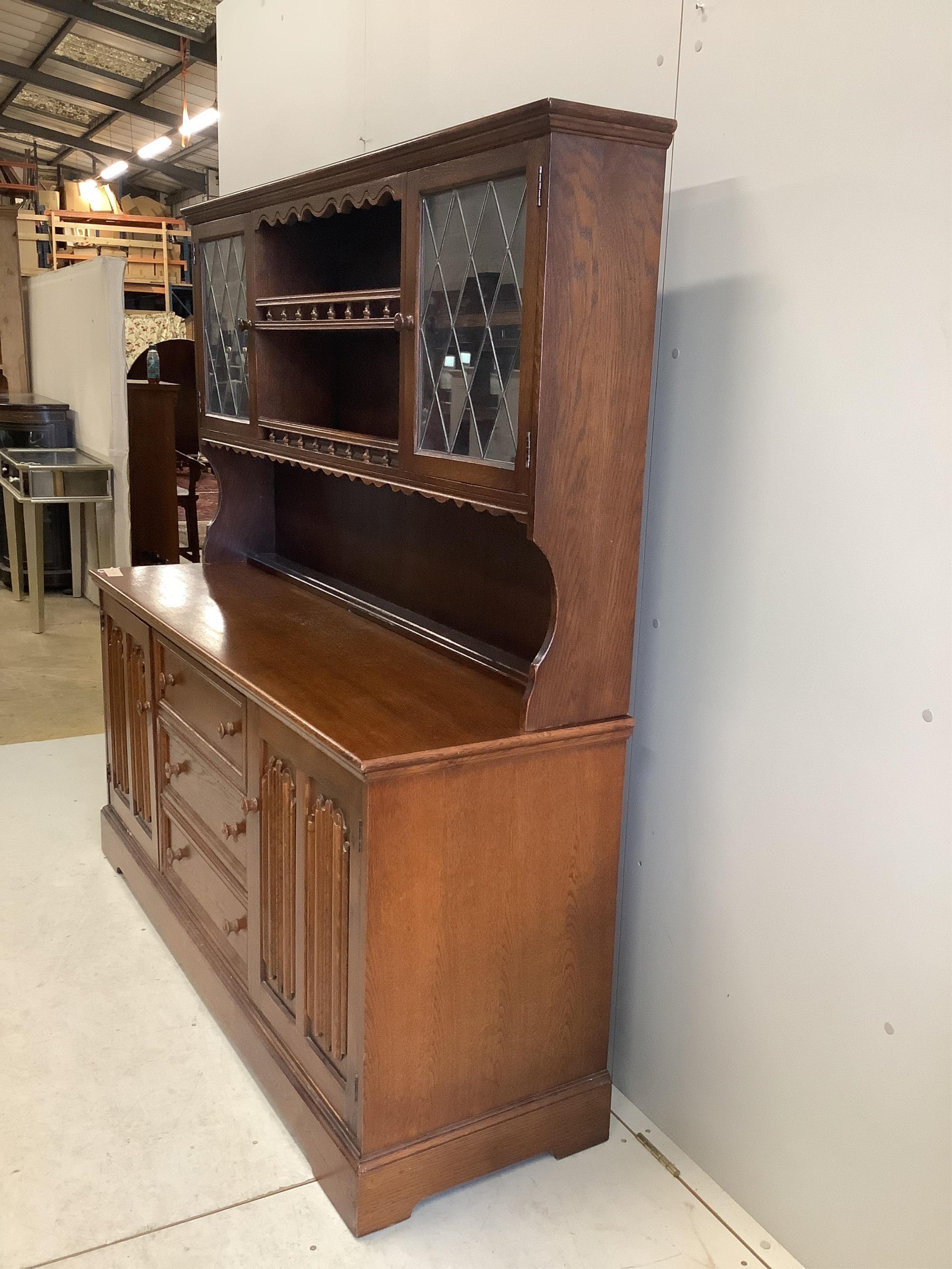 A reproduction oak dresser, the cupboards with linen fold carved fronts, width 160cm, 48cm, height 164cm. Condition - fair to good